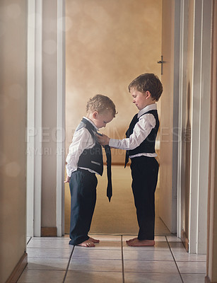 Buy stock photo Shot of a sweet little boy helping his younger brother get dressed in a suit