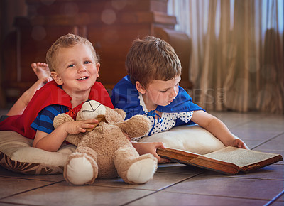 Buy stock photo Portrait of a happy little boy listening to his brother read a story while they lie on the floor at home