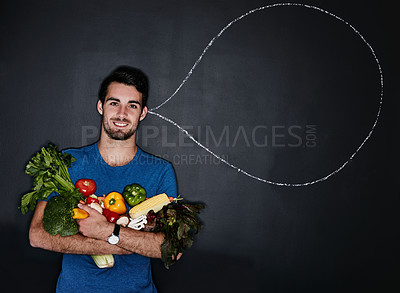 Buy stock photo Studio portrait of a young man carrying vegetables next to an illustration of a thought bubble against a dark background