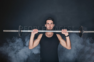 Buy stock photo Studio shot of a young man working out with a barbell against a gray background