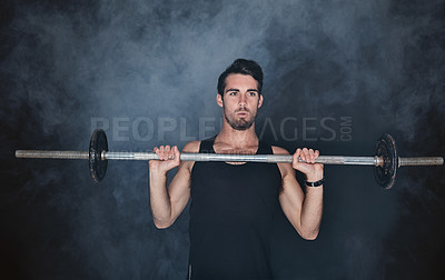 Buy stock photo Studio shot of a young man working out with a barbell against a gray background