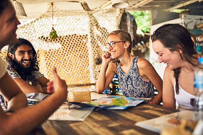 Buy stock photo Shot of a group of young friends chatting while relaxing in a restaurant