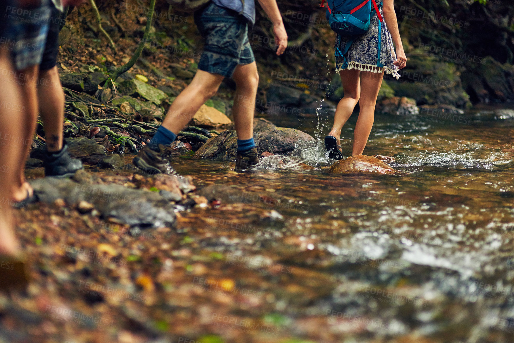 Buy stock photo Cropped shot of a group of unidentifiable hikers crossing a stream while exploring in the woods