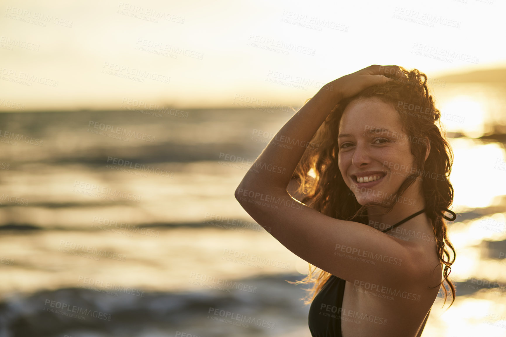 Buy stock photo Portrait of a happy young woman posing on the beach at sunset
