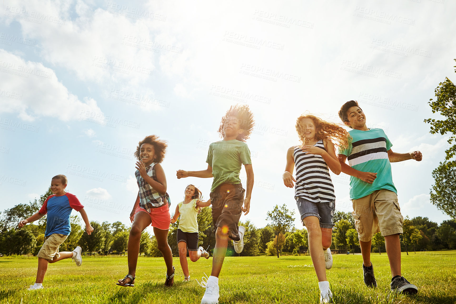 Buy stock photo Happy friends, summer and running with kids in nature for fun, playful day or sunshine at park. Diversity or group of excited children or youth enjoying sunny outdoor holiday on grass field together