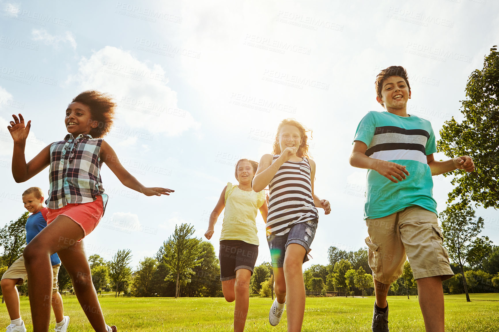 Buy stock photo Happy friends, diversity and running with children in nature for fun, playful day or summer at park. Group of excited kids or youth enjoying sunny outdoor holiday or weekend on grass field together