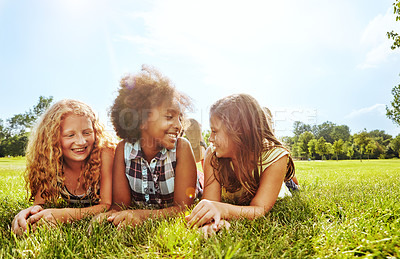 Buy stock photo Shot of three young girls lying together on the grass outside