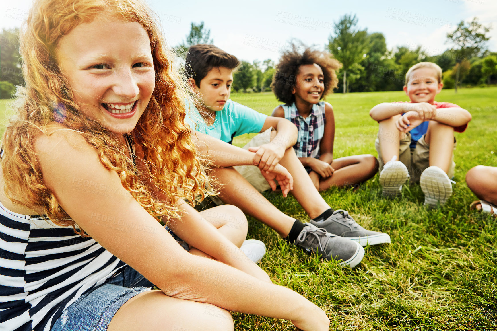 Buy stock photo Portrait of a young girl sitting together with her friends on the grass outside