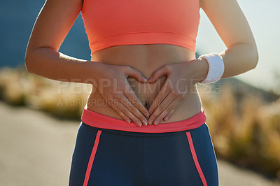 Buy stock photo Shot of an unrecognizable young woman making a heart with her hands on her stomach