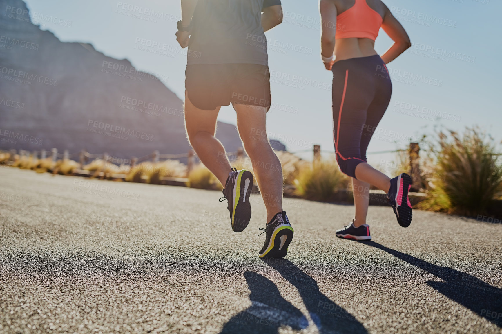 Buy stock photo Rearview shot of two unrecognizable young people running on the road