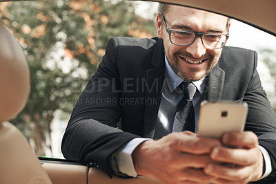 Buy stock photo Shot of a handsome businessman sending a text while leaning on his car window