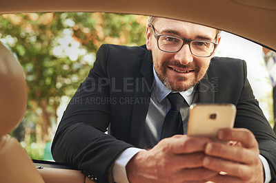 Buy stock photo Portrait of a handsome businessman sending a text while leaning on his car window
