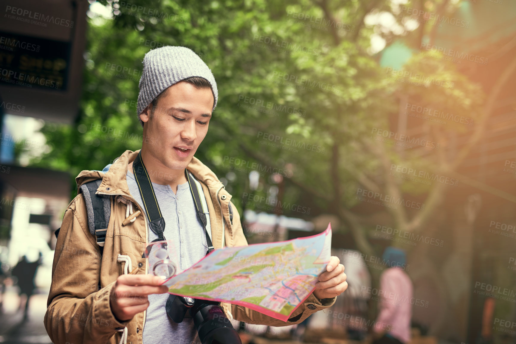 Buy stock photo Cropped shot of a young man using a map while travelling in the city