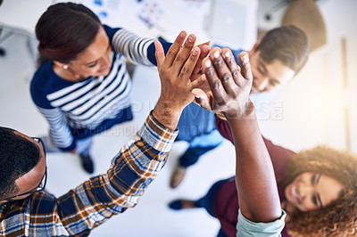 Buy stock photo High angle shot of a team of designers high fiving together  in an office