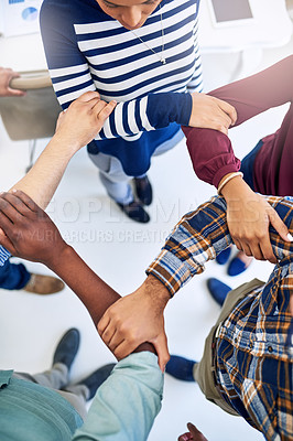 Buy stock photo High angle shot of a team of designers joining their hands together in unity