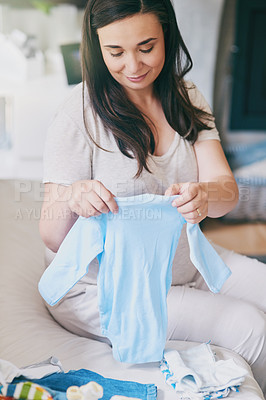 Buy stock photo Cropped shot of a pregnant woman sorting baby clothes