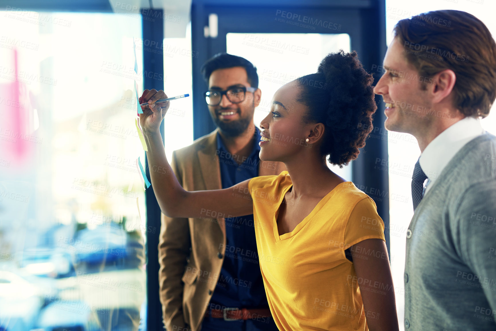 Buy stock photo Cropped shot of a group of businesspeople brainstorming with notes on a glass wall in an office