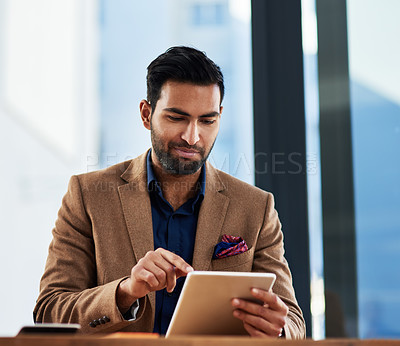 Buy stock photo Cropped shot of a young businessman working on a digital tablet in an office