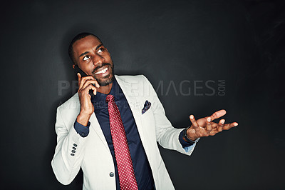 Buy stock photo Cropped shot of a young businessman talking on a cellphone against a dark background