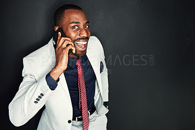 Buy stock photo Portrait of a young businessman talking on a cellphone against a dark background