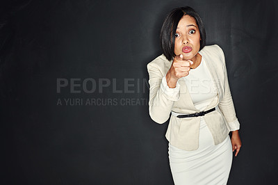 Buy stock photo Portrait of a young businesswoman pointing her finger against a dark background