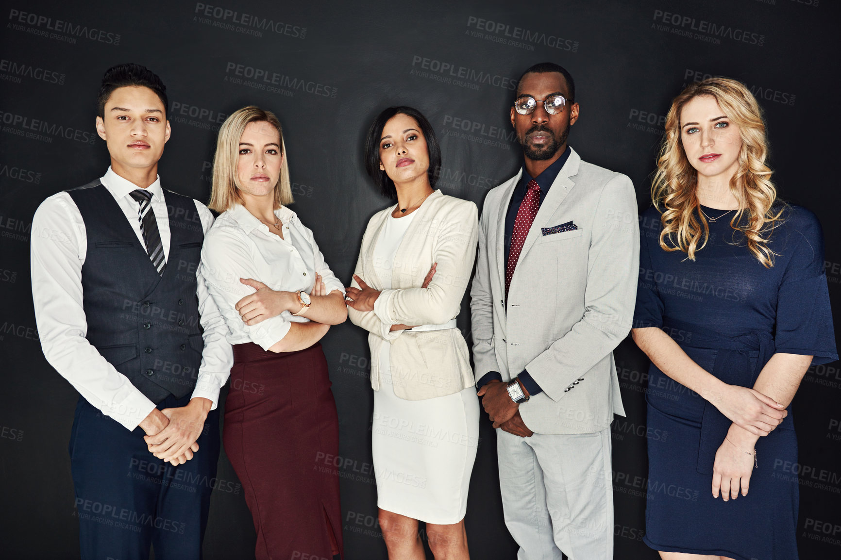 Buy stock photo Portrait of a group of confident young businesspeople standing against a dark background