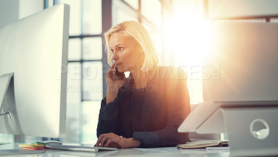 Buy stock photo Shot of a professional businesswoman using a computer and phone at work
