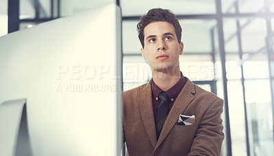 Buy stock photo Shot of a thoughtful young businessman working at his desk in a modern office