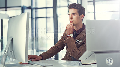 Buy stock photo Shot of a young businessman using a computer at his work desk