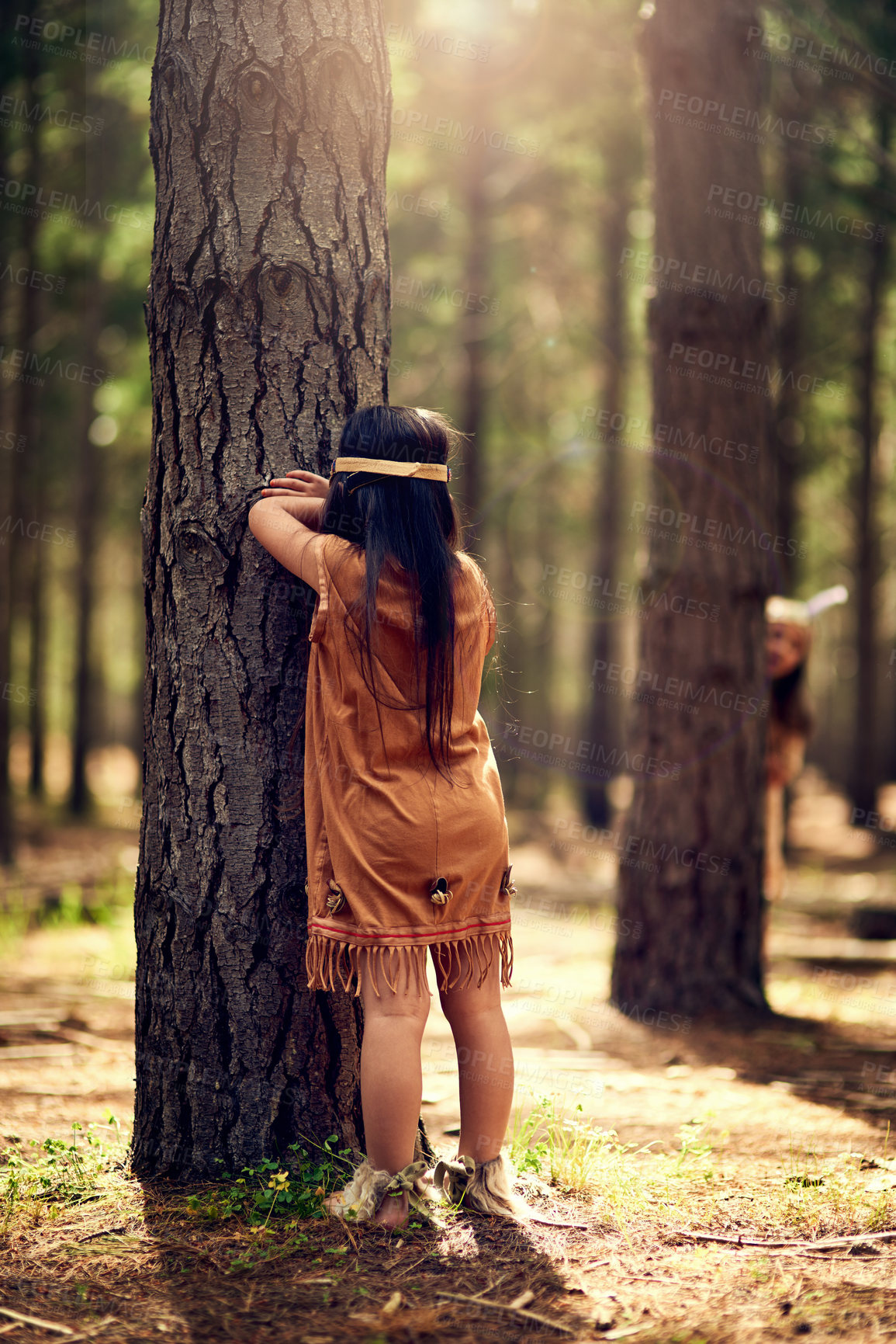 Buy stock photo Native American children, girls and forest for hide and seek with play, heritage or dress up in nature. Kids, siblings and happiness in woods for fun and bonding in traditional clothes with trees