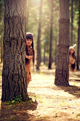 Buy stock photo Portrait of two little girls hiding behind trees while playing dressup in the woods