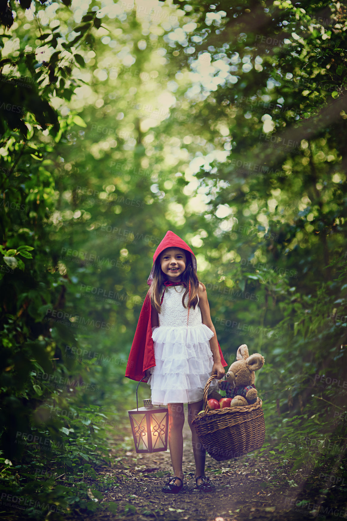 Buy stock photo Picnic, girl and child with basket, portrait and smile for red cloak, nature and forest for fun and relax. Woods, outdoor and kid with teddy bear, apples and food in park, trees and happy youth 
