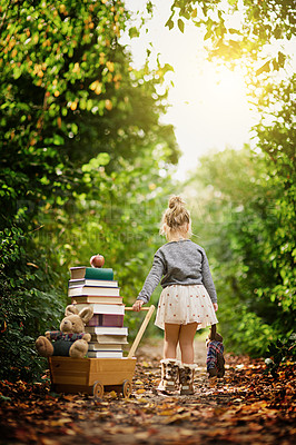 Buy stock photo Shot of a little girl pulling her toy cart filled with books through a forest