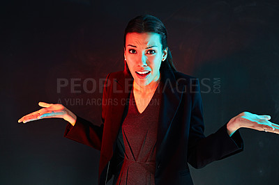 Buy stock photo Portrait of a confused businesswoman posing against a dark background