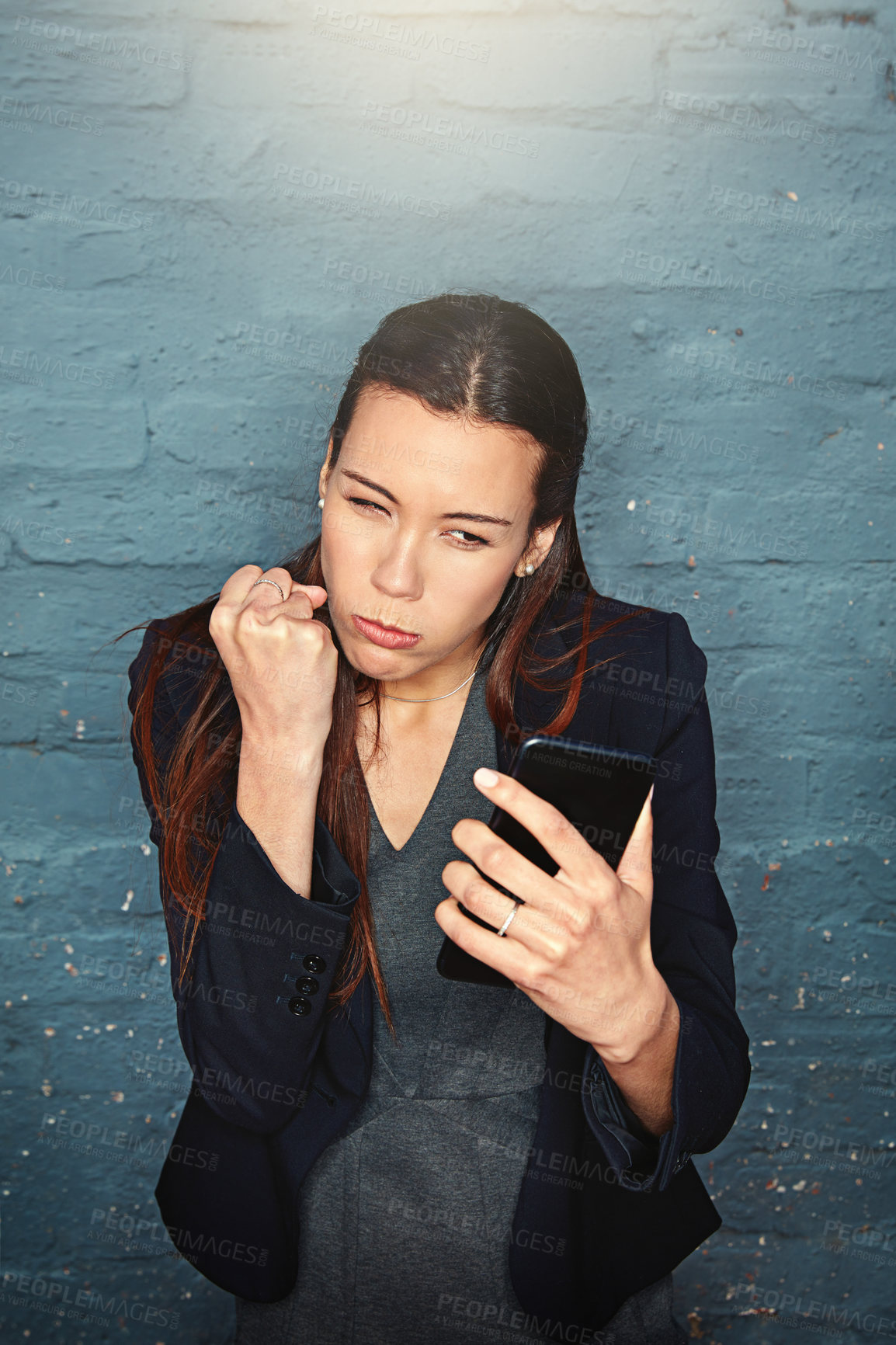 Buy stock photo Shot of an enraged businesswoman shaking her fist at her phone