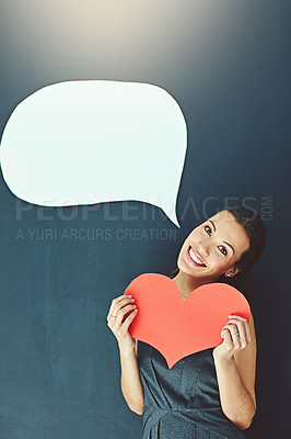 Buy stock photo Portrait of a young woman posing with a heart against a gray background