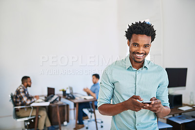 Buy stock photo Portrait of a young entrepreneur using a phone at work with his team in the background