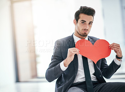 Buy stock photo Portrait of a trendy young businessman posing with a paper heart in the office