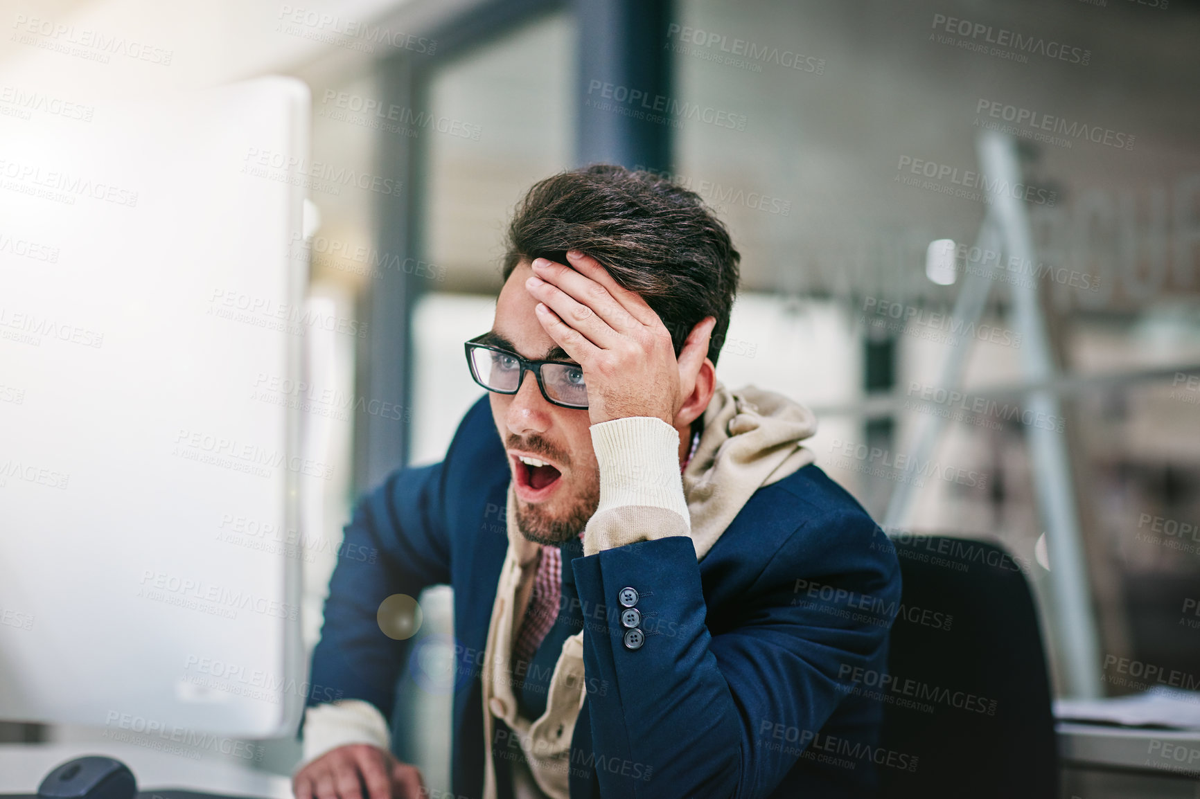 Buy stock photo Shot of a trendy young businessman looking surprised while using his computer in the office