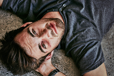 Buy stock photo High angle portrait of a beaten and bruised young man lying down on the floor