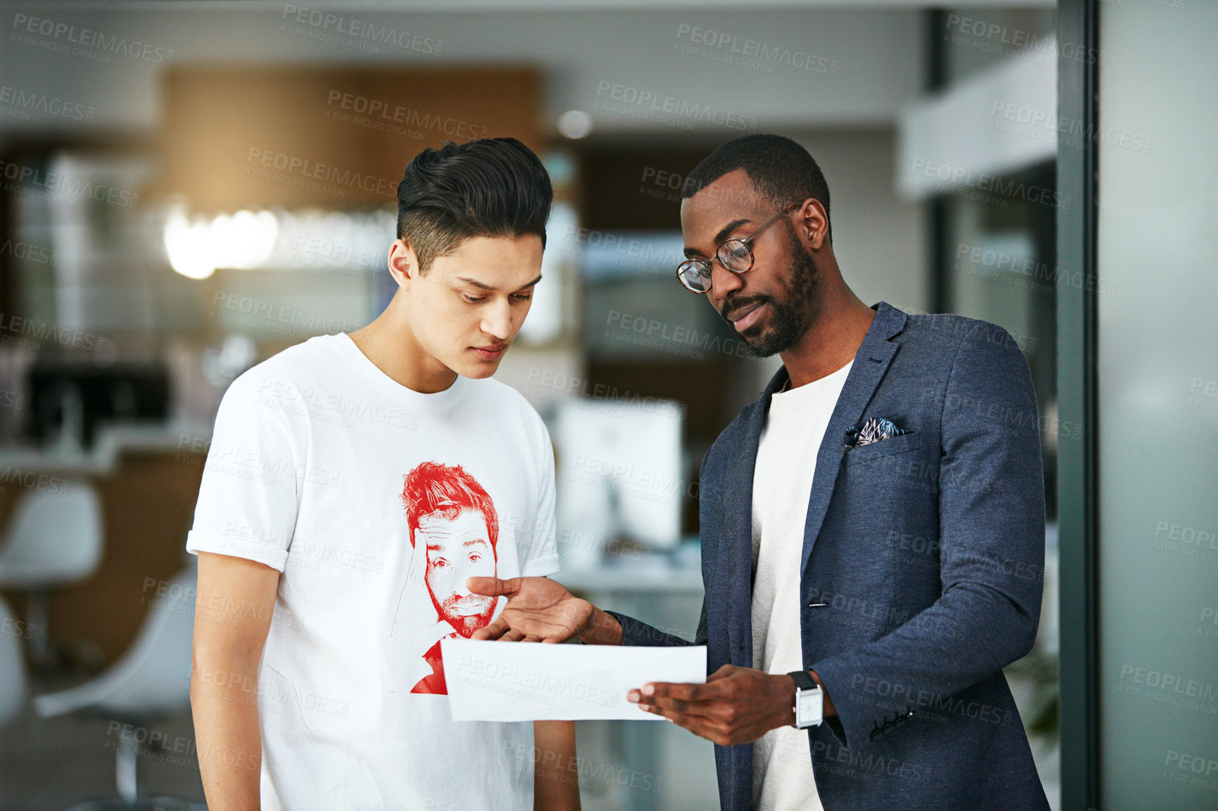 Buy stock photo Shot of two colleagues reading a document together at work
