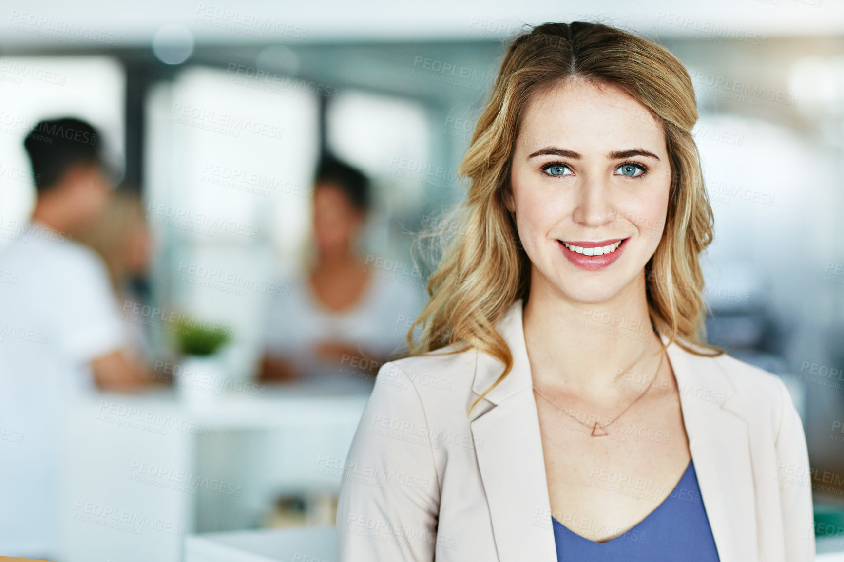 Buy stock photo Portrait of an ambitious young woman standing in a modern office with her colleagues in the background