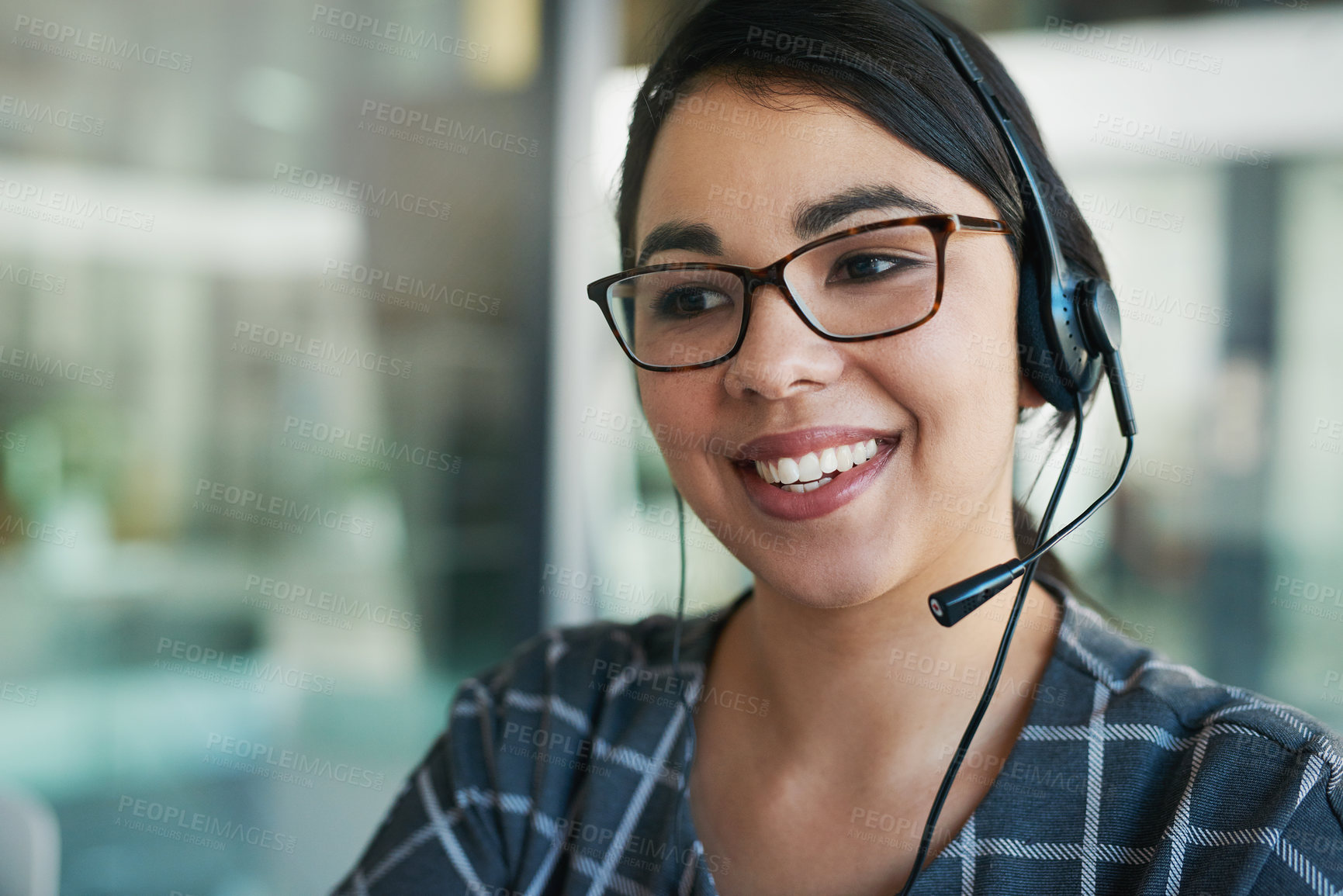 Buy stock photo Shot of a happy young woman using a headset at work