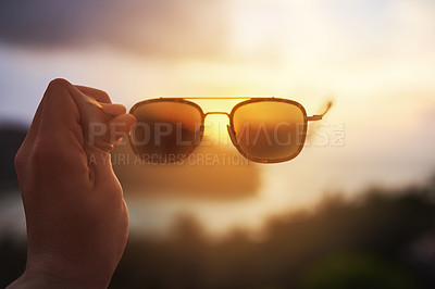 Buy stock photo Cropped shot of an unidentifiable tourist holding up a pair of sunglasses over a tropical view