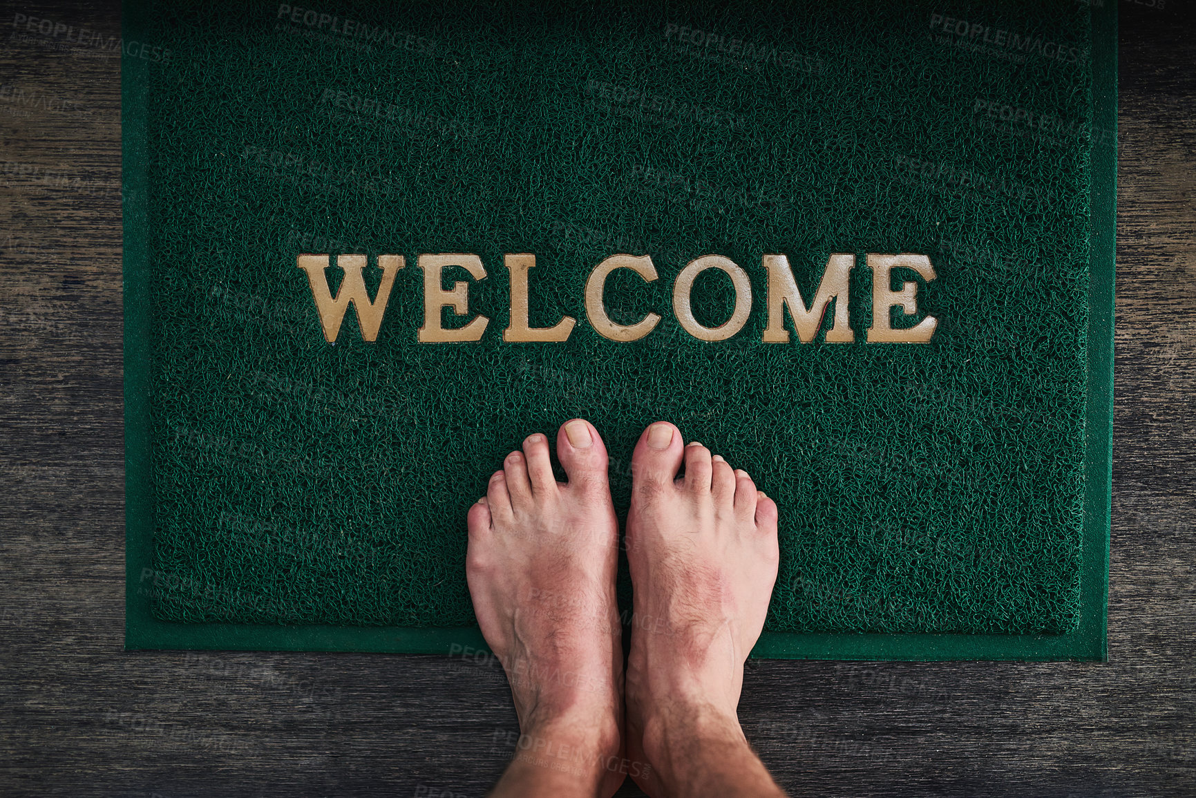 Buy stock photo High angle shot of a man's bare feet standing on a welcome mat