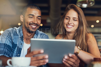 Buy stock photo Cropped shot of a young couple using a digital tablet while sitting in a cafe