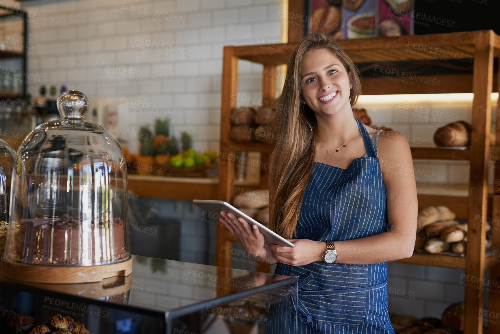 Buy stock photo Portrait of a young business owner using a digital tablet in her bakery