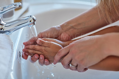 Buy stock photo Closeup shot of a mother helping her little girl wash her hands at the bathroom sink
