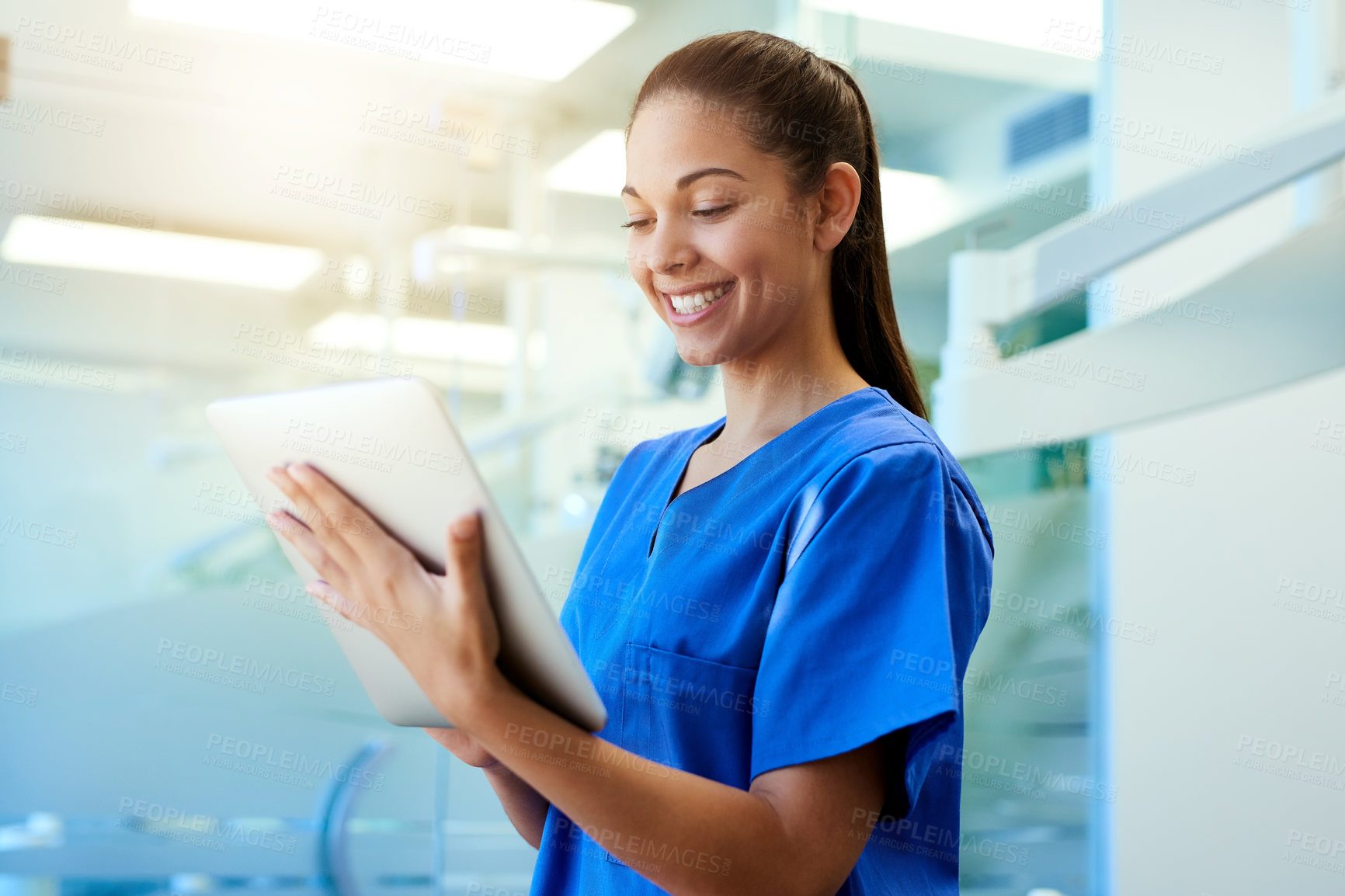 Buy stock photo Shot of a young nurse using a tablet while standing inside a clinic