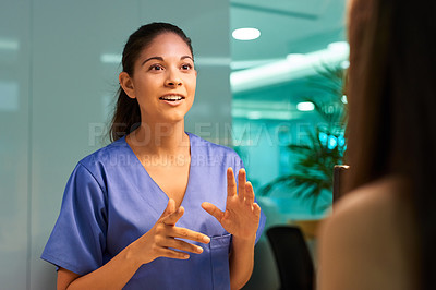 Buy stock photo Shot of a young nurse discussing a procedure with her patient in the clinic